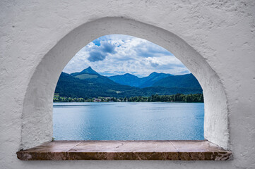 view through a stone window to the beautiful landscape of the Wolfgangsee in Austria