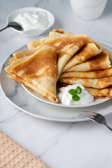 Stack of russian thin pancakes blini with fresh sour cream