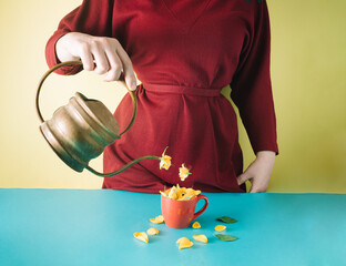 The girl holds a vintage teapot and pours yellow roses into a cup. Minimal layout spring composition.