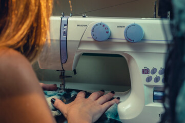 close up of caucasian woman working with blue fabrics on sewing machine