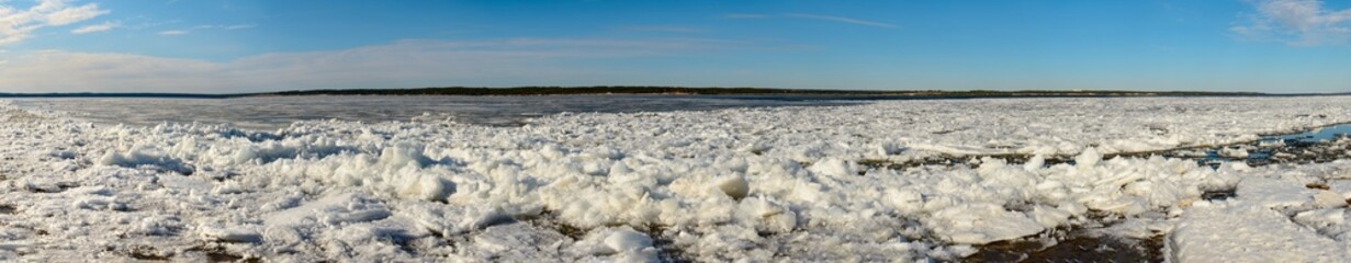 Spring day with a wide river with melting ice. Ice drift.