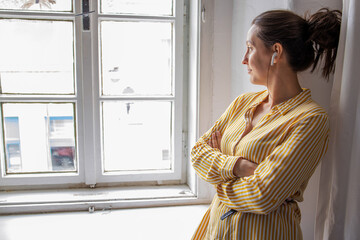 Young woman listening music and looking out of window