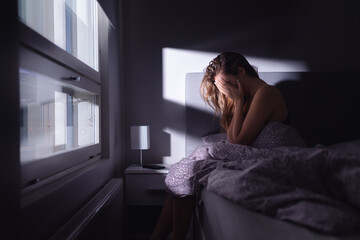 Sad depressed woman in bed. Lonely person with stress, insomnia and trouble sleeping. Anxiety, sorrow, solitude, grief or panic. Restless tired and desperate girl crying with emotion. - obrazy, fototapety, plakaty
