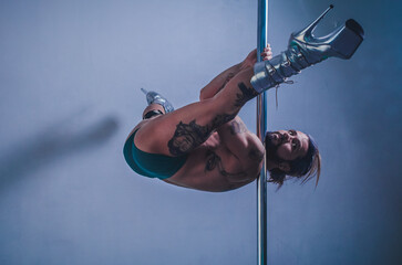 Pole dance man, young venezuelan doing striptease in the pole dance studio with open legs
