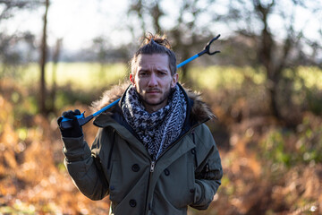 A portrait of a young bearded man with a litter picker ready to do a litter pick and clean up the...