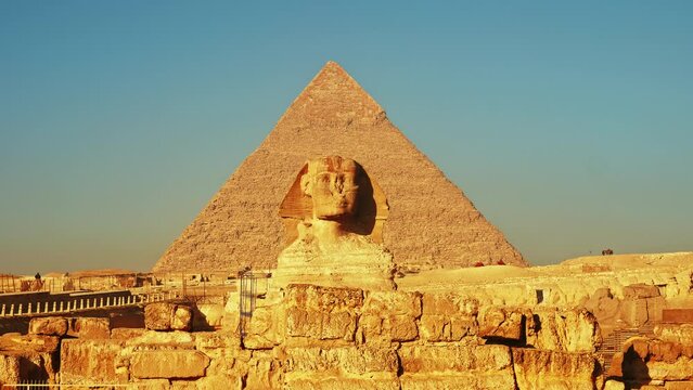 Pyramid of Khafre or Chephren and Great Sphinx of Giza. Ancient Egyptian mortuary temple construction from limestone blocks, statue of mythical creature. Camels moving along road. Sunny day