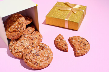 oatmeal cookie in gift box over pink background with copy space. Gift box of cookies with shadows and sunlight.
