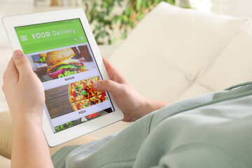 Man using tablet for ordering food online at home, closeup. Delivery service