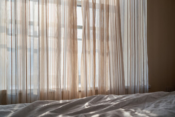 Light linen style textured curtains letting morning sunlight into a bedroom.
