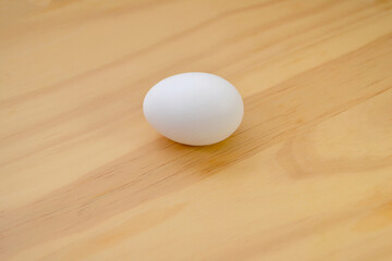 A Fresh White Chicken Egg on a Wooden Background