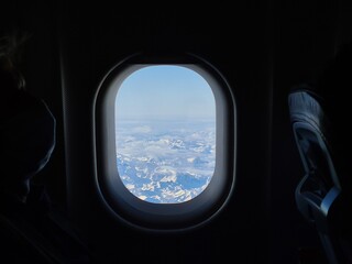 Naklejka premium Panorama of the snow capped Alps in the window of an airplane flying over them