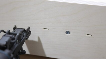 Process of connecting parts of a furniture frame using an automatic pneumatic stapler. Furniture production. Close up work of a professional nail gun in production. Slow motion video in 4k format