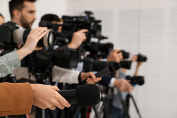 Group of journalists with cameras waiting for official person indoors, closeup