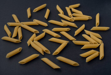 Raw pasta scattered on a dark background