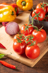 Table with red and yellow peppers, peppers, onions and garlic and tomatoes, over rustic wood, black background, selective focus.
