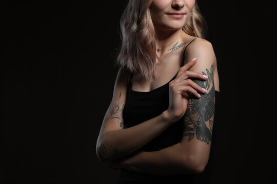 Beautiful woman with tattoos on body against black background, closeup. Space for text