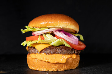 CHEESBURGER  FAST FOOD ON BLACK BACKGROUND.
HOMEMADE SANDWICH