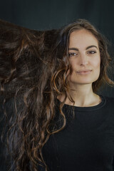 Portrait of a beautiful young Italian woman with very long brown hair who is smiling and looking at the camera