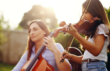 Music runs in the family. Cropped shot of a mother and daughter playing musical instruments together in the backyard.
