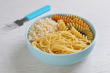 Bowl with different types of tasty pasta on white wooden table