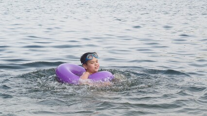 Kid on beach with swimming circle. Boy swimming in sea. Children and holiday concept