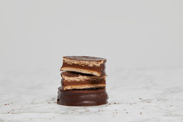 Dark chocolate and dulce de leche alfajores on a marble table.