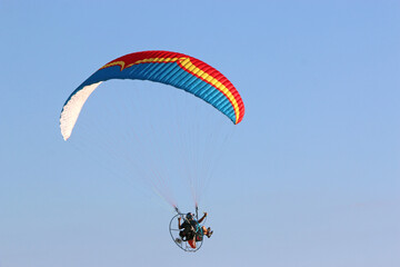 Paramotor pilot flying in a blue sky	