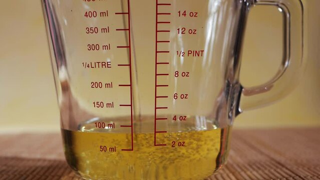 Filling measuring glass jug with vegetable oil 
