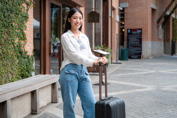 Asian woman tourist standing with smiling and holding black luggage to preparing on holiday trip