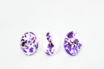 Three Easter eggs with pieces of decorated foil stand in a row on a white background. Religious holiday of Holy Easter
