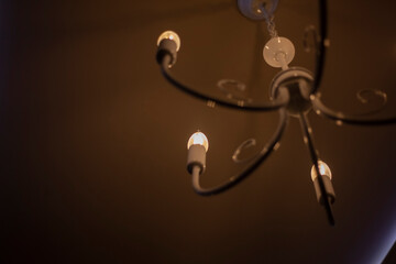 Chandelier in room. Old lamp under ceiling. Interior details. Dim light from lamps. Background decoration of ceiling.