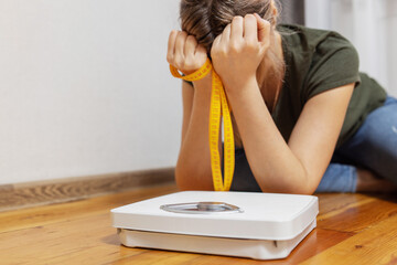 White scale and depression, upset and sad woman with measuring tape on wooden floor