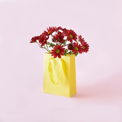 Bouquet of spring flowers in the yellow shopping bag on a pink background. Aesthetic shopping idea.