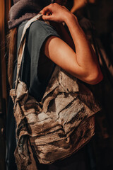 Fototapeta na wymiar Female hand holding brown fabric handbag. Style, design of women's clothing and accessories.