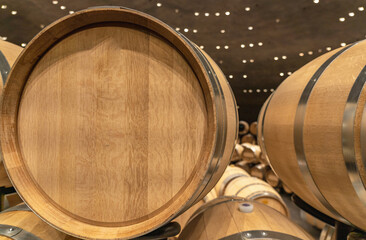 New oak barrels with stainless rings close-up in a winery with a place for an inscription