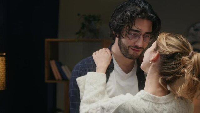 Young couple dancing in living room in evening. Romantic relationships and love. Happy woman and man hugging and enjoying slow dance at home, celebrating anniversary.