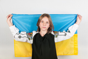 Stop war in Ukraine. Blond teen girl in traditional Ukrainian clothes with Ukrainian flag. Peace in...