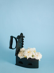 1920s charcoal iron box with white rose on pastel blue background. Retro layout bouquet. Antique...