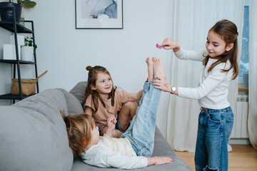 Experimenting girls tickling boy's feet with feather.