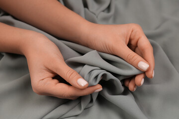 Woman touching smooth grey fabric, closeup view