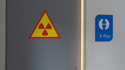 Xray warning signs posted on locked door and wall. Radioactive sign in yellow colour on door. X-ray cabinet.