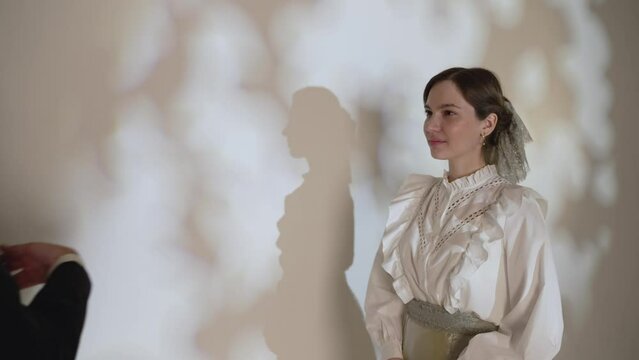 First meeting. A girl in an old dress stands in the background and waits for the prince. A young guy in a classic suit meets and flirts with a girl. Guy and girl in old clothes.