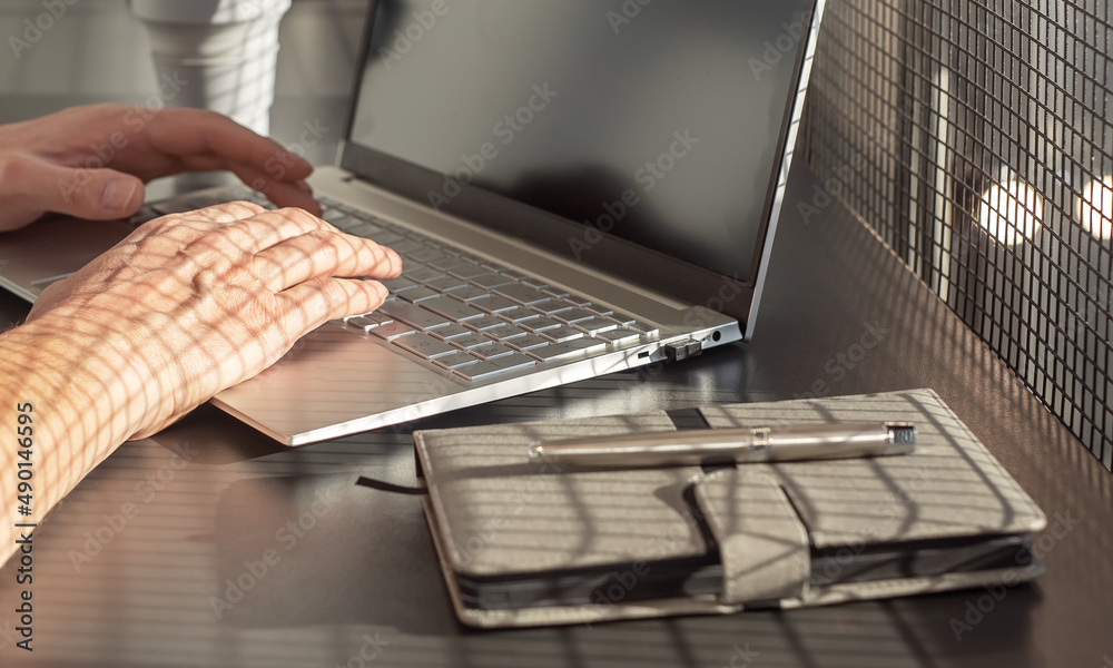 Poster Man hands closeup typing on laptop keyboard. Businessman sitting at office or home desk with diary and silicon mug and writing text or mail on computer. High quality photo