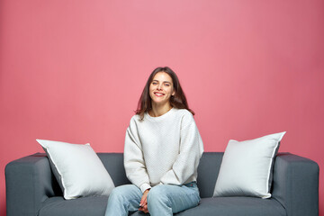 Happy overjoyed young girl sitting on sofa, smiling, satisfied with ordered goods or service, watching comedy stand-up