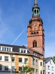 View of european building exterior and St. Laurentii church clock tower at intersection of Kirchenstrasse and feldschmiede in Itzehoe, Germany with clear blue sky background.