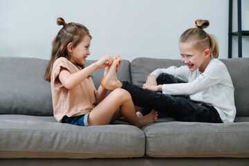 Little girl trying to tickle boy's foot, they both laugh.