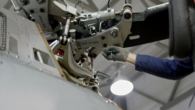 unrecognizable mechanic is turning nut on helicopter propeller. Large helicopter that is in hangar for repair and rebuild, on which blades are about to be removed, maintenance of air vehicle.
