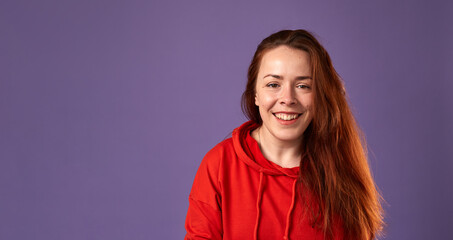 Smiling caucasian red hair woman on purple background