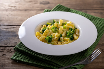 pasta with broccoli on a white plate and wooden table