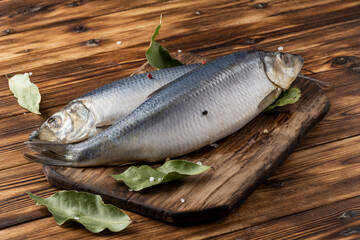 two salted herring on a wooden table with spices